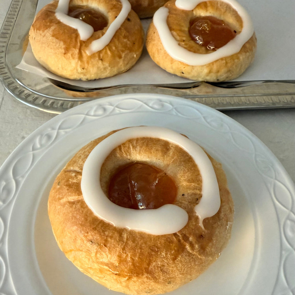 Pyöreä pulla, jossa keskellä aprikoosihilloa ja valkoista pomadaa 